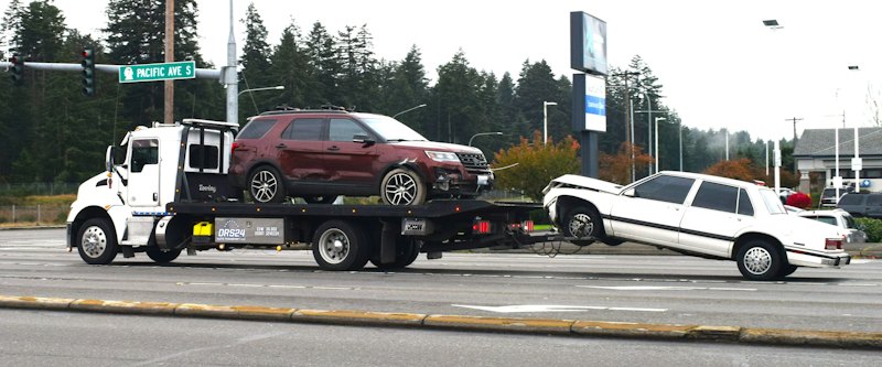 Tow truck loading a car onto a flatbed for pickup