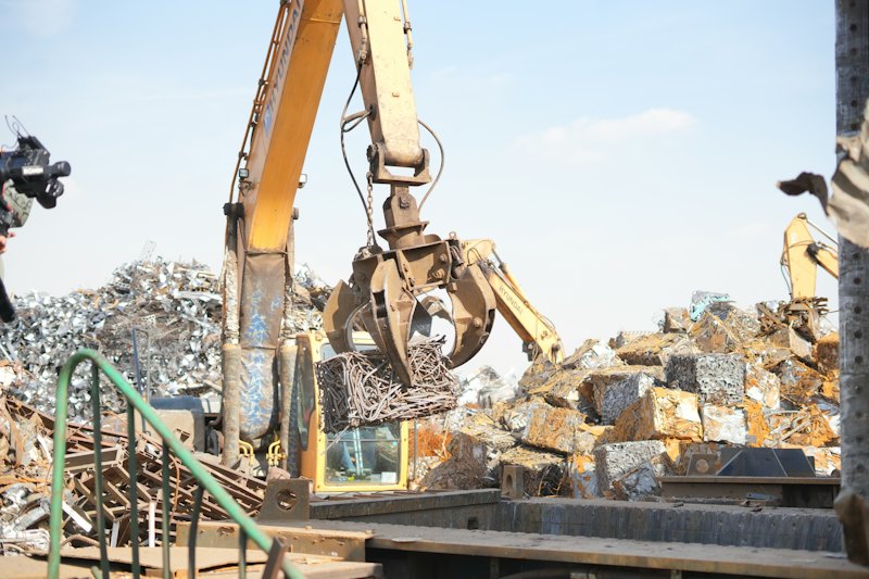 Excavator sorting a pile of scrap metal for recycling