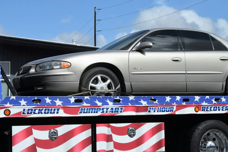 Flatbed tow truck carrying a silver car